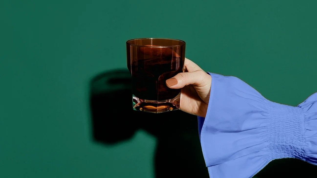 persona sosteniendo un vaso de jugo de ciruela